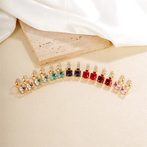 Detail view of colorful square zircon hoop earrings on a luxury marble display