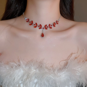 Detail of elegant silver necklace featuring red teardrop pendant and leaf design