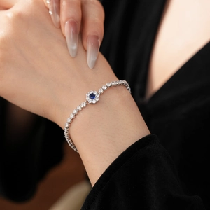 Close-up of silver flower bracelet with blue center stone and white zircons on wrist