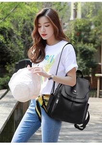Close-up of black leather texture and metal kangaroo logo on women's anti-theft backpack
