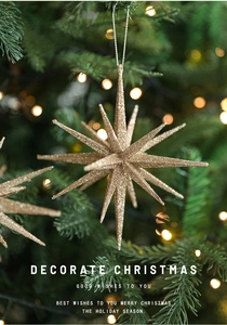 Close-up of a golden glitter star ornament hanging on a Christmas tree with bokeh lights