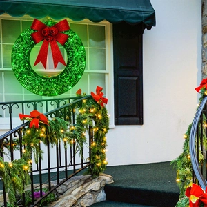 Close-up of green Christmas wreath with red bow and LED lights hanging on window