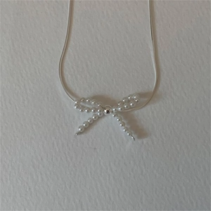Detail shot of 925 sterling silver bow pendant necklace with small white pearls