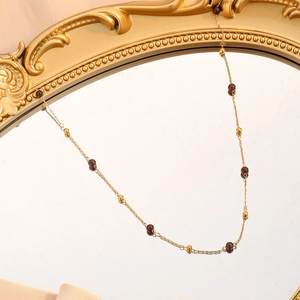 Vue détaillée de la chaîne à perles dorées vintage avec pierres de grenat rouge foncé