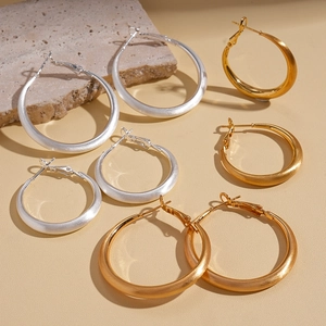 Brushed 18k gold and silver metal hoop earrings in various sizes on stone props