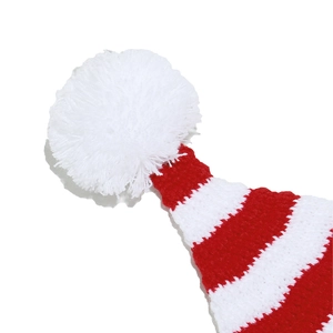 Detailed close-up of a red and white striped knit Christmas hat with a fluffy white pompom