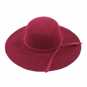 Detail of burgundy wide brim wool felt hat with decorative bow ribbon on plain background