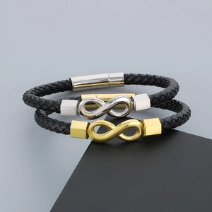 Detail view of woven black leather bracelets with gold and silver infinity symbols