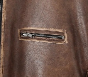 Détail de la texture cuir PU marron vintage et fermeture éclair métallique sur le bomber