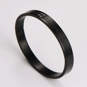 Close-up of black stainless steel bracelet with Greek key pattern and inlaid diamonds