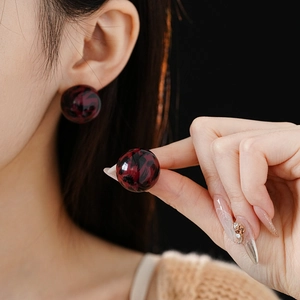 Close-up of red marble pattern leopard earrings worn by a model in dark lighting