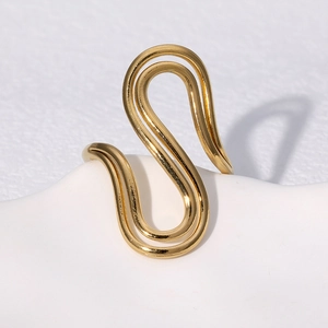 Minimalist gold S-shaped wavy stainless steel ring on a white display stand