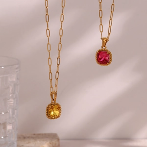 Detail of gold paperclip chain necklace with yellow and pink square gemstone pendants