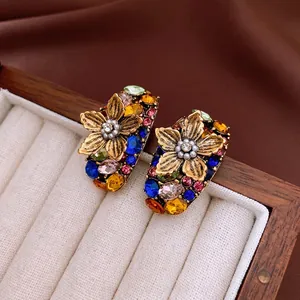 Vintage floral pearl earrings with colorful rhinestones on a beige jewelry box