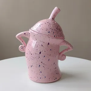 Pink ceramic canister with blue spots and curved handles in a cartoon character design