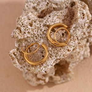 Vue macro de boucles d'oreilles créoles doubles en acier doré 18 carats sur pierre