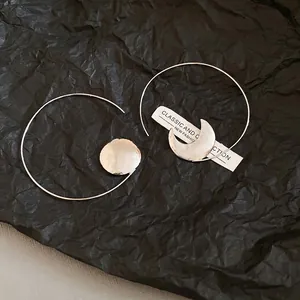 Asymmetric geometric hoop earrings with crescent moon and textured silver disc charms