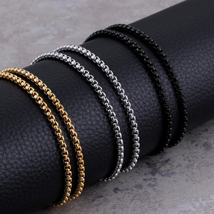 Stainless steel box chains in gold, silver, and black colors on black leather stand