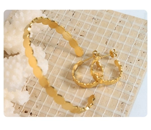 Minimalist gold oval link jewelry set with bracelet and earrings on textured tile