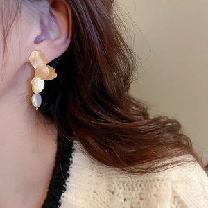 Close-up of golden petal earrings with freshwater pearl drop on a female model