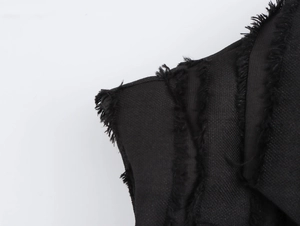 Gros plan d'une robe noire sans manches avec texture tissée et détails de bords effilochés