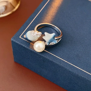 Detailed close-up of a sea-themed ring with large pearl and blue enamel star on jewelry box
