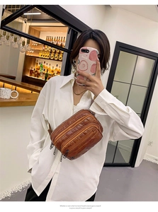 Sac bandoulière marron en similicuir crocodile avec plusieurs poches zippées sur un mannequin
