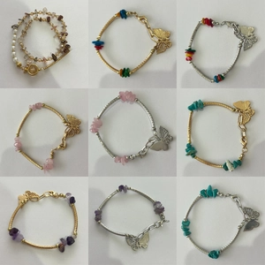 Détail de bracelets superposés avec pendentifs papillon et pierres naturelles colorées