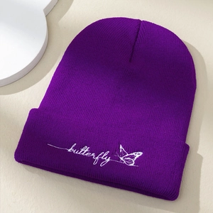 Gros plan détaillé de la broderie papillon sur le rebord d'un bonnet en maille violet