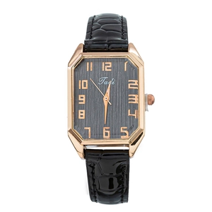 Macro shot of rectangular rose gold case and black leather strap with crocodile pattern
