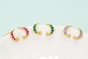 Detail of colorful celestial stud earrings with pink, green, and purple micro-set stones
