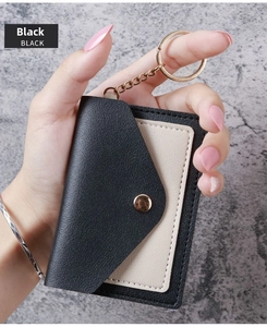 Detail view of black lychee leather card holder with warm white interior and gold keychain