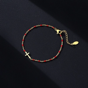 Close-up of gold-plated stainless steel cross bracelet with red enamel beads and clasp