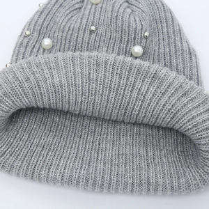 Detailed close-up of grey ribbed knit hat with white faux pearls and silver beads