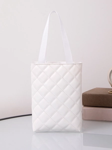 Detail of white quilted tote bag with woven handles on glass table with elegant props