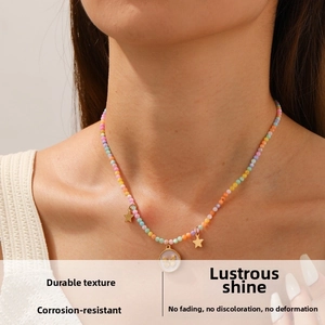 Détail d'un collier de perles colorées avec pendentifs papillon et étoile sur un modèle