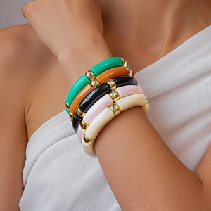 Dettaglio di 5 bracciali impilabili in acrilico colorato con distanziatori dorati