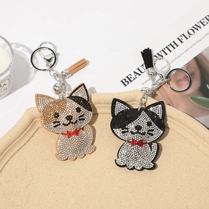 Detailed view of cat keychains with rhinestones, leather tassels, and metal lobster clasps