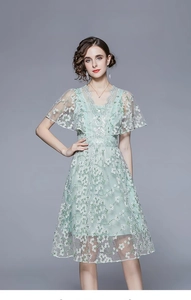 Detailaufnahme von V-Ausschnitt mit Spitze und weißen Blumenstickereien am Kleid