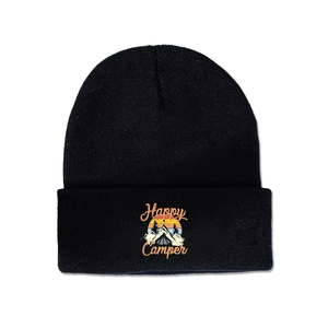 Close-up of Happy Camper embroidered patch with forest and sunset on black knit beanie