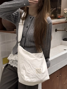 Lifestyle shot of a white canvas tote bag with pink star print and woven label detail
