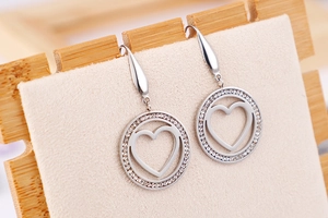 Detailed view of silver heart-shaped hollow earrings with shimmering cubic zirconia stones