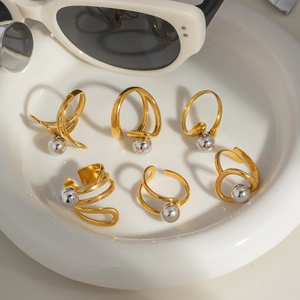 Dettaglio di anelli con perle dorate su vassoio in ceramica bianca, stile retrò chic