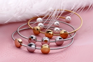 Macro shot of minimalist stainless steel cable bracelets in gold, rose gold and silver