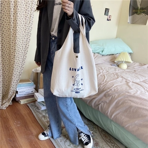 Gros plan d'un sac cabas en toile blanc cassé avec lapin bleu et boucle métallique