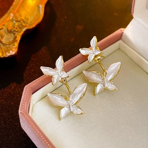Detailed close-up of double butterfly earrings with white enamel wings in a pink box