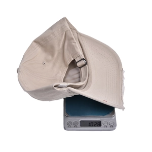 Detail shot showing the weight of 102.8g for the distressed cotton baseball cap on a scale