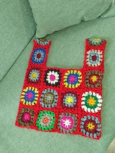 Detailed view of handmade crochet granny square patterns on a red woven handbag