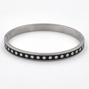 Detail view of a black enamel titanium steel bangle with silver polka dot patterns