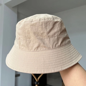 Beige nylon bucket hat with wide brim and adjustable drawstring for summer sun protection